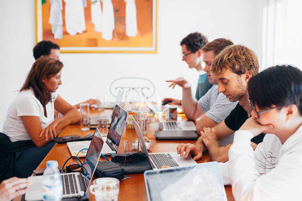 Wide-angle banner showing a bright, modern office space where a diverse team of professionals is collaborating.