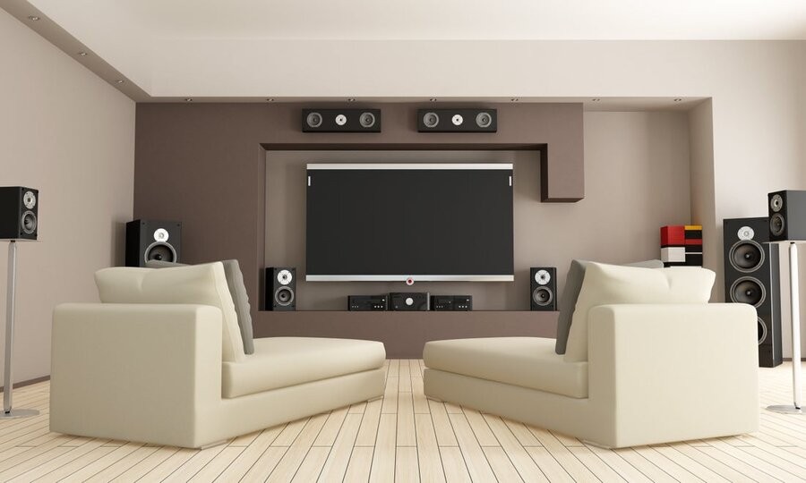 A media room setup with seating, large screen display, and various high-end speakers surrounding it.