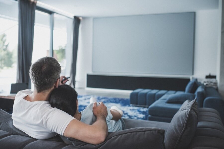 A couple sitting in front of their AV setup with a large display.