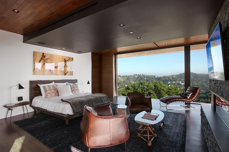 luxurious bedroom with floor-to-ceiling windows overlooking a forest’s tree tops