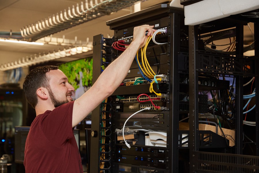 Man installing cabling in a smart home server room. 